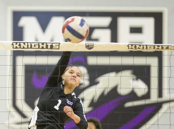 Knight's women's volleyball player spiking the ball over a net during a game. 